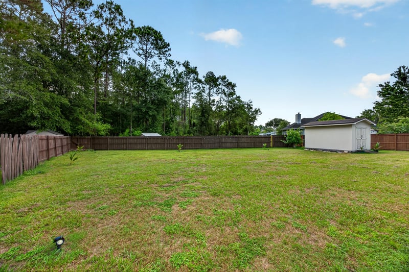 Open backyard lawn with wood fence at 8921 Needlepoint Pl, Jacksonville, FL 32244