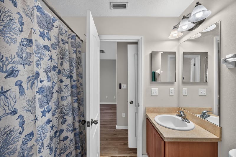 Bathroom with floral shower curtain and double vanity at 7723 Playschool Ln, Jacksonville, FL