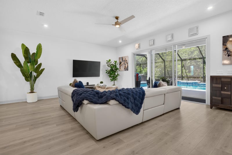 Living room with sectional and pool visible through windows at 785 Back Creek Dr, St. Augustine, FL 32092