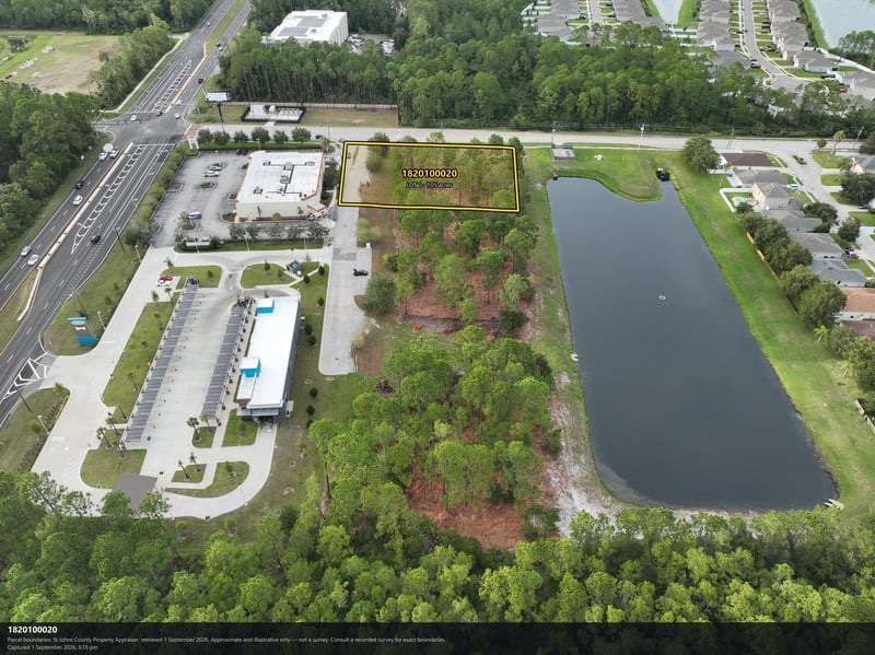 Aerial view of the building and pond beside the tree-lined parcel at 4900 US-1, St. Augustine, FL 32086