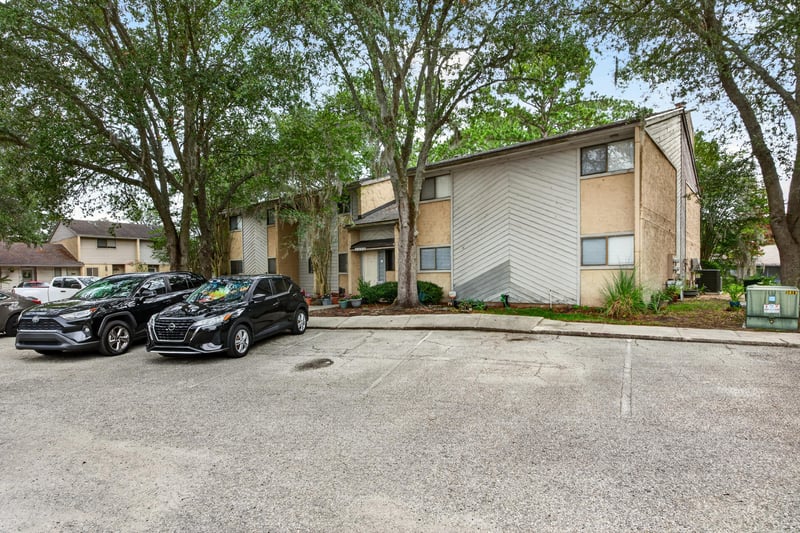 Condo building exterior with parking and trees in Jacksonville, FL