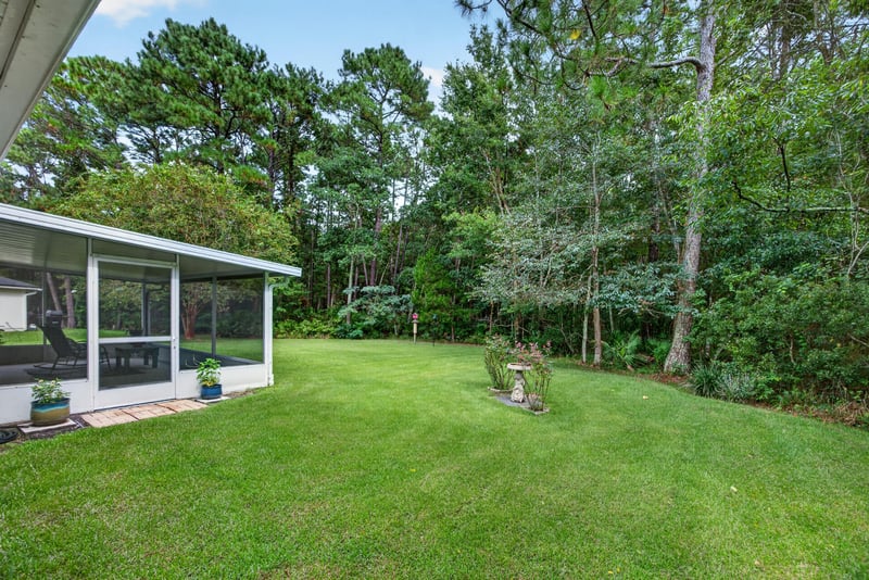 Backyard lawn bordered by wooded tree line at 13514 Las Brisas Way N, Jacksonville, FL