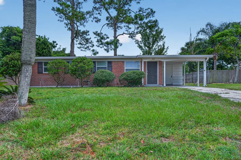 Front exterior view of brick home and lawn at 87 Saratoga Cir S, Atlantic Beach, FL