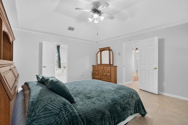 Primary bedroom with wood headboard and tray ceiling at 12810 Swamp Owl Ln