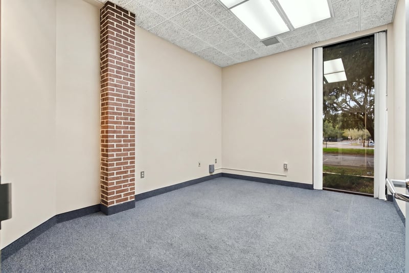 Empty carpeted office with brick accent wall at 101 Scholars Wy
