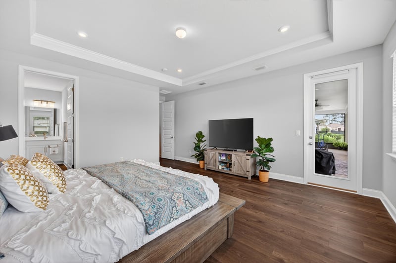 Primary bedroom with TV and wood floors at 85491 Fall River Pkwy, Fernandina Beach, FL 32034