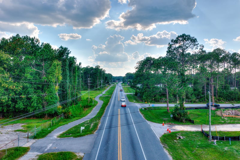 Aerial of Co Rd 218 with passing traffic and wooded shoulders at 4393 Co Rd 218, Middleburg, FL 32068