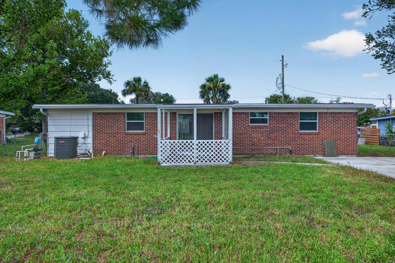 Rear exterior of brick home with lawn at 87 Saratoga Cir S, Atlantic Beach, FL