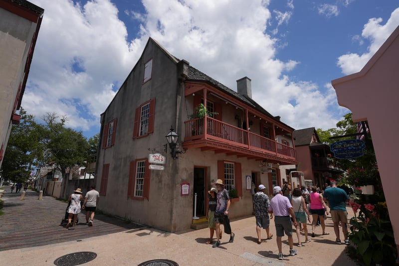 Street-level view of the stuccoed building corner with balcony and pedestrians at 29 Cuna St, St. Augustine, FL 32084