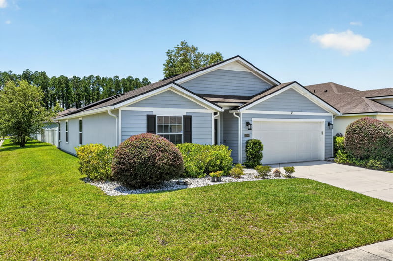 Front exterior with gray siding and double-car garage at 10066 Andean Fox Dr, Jacksonville, FL 32222