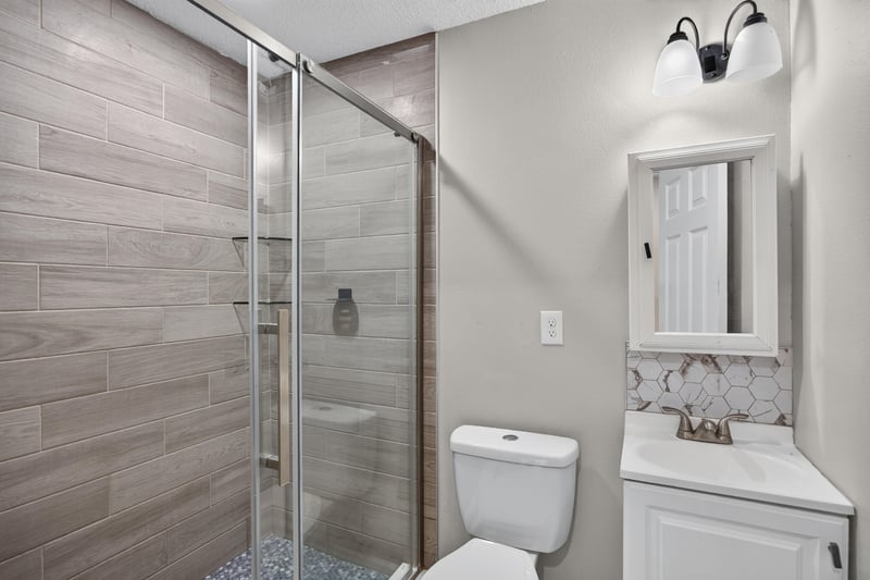 Bathroom with vanity, toilet, and tile shower at 7015 Miss Muffet Ln N, Jacksonville, FL 32210