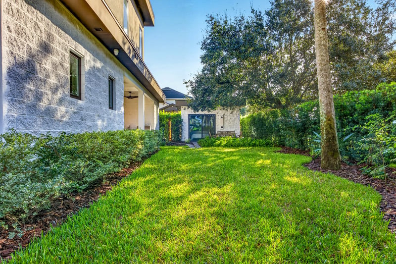 Backyard lawn with palm trees and privacy hedge at 722 3rd Ave N, Jacksonville Beach, FL