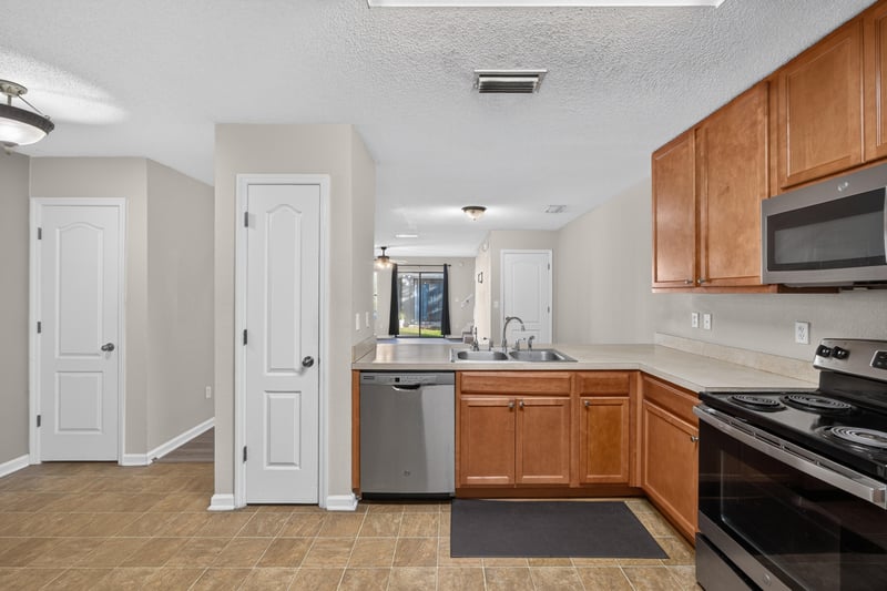 Kitchen pass-through with tile flooring and cabinets at 7723 Playschool Ln, Jacksonville, FL