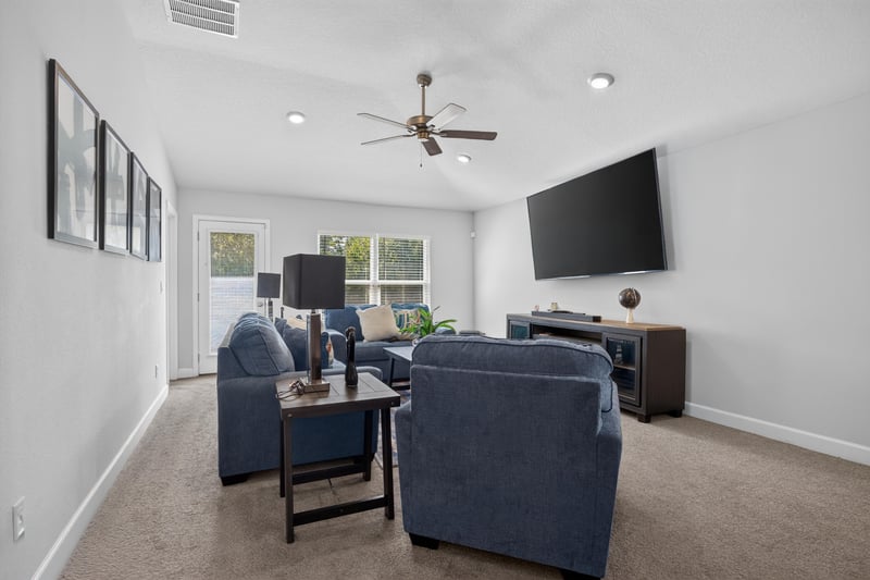 Living room with blue sofas and wall-mounted TV at 9846 Olivia St, Jacksonville, FL