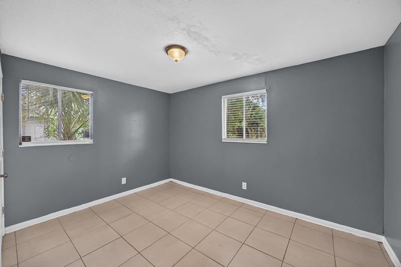 Empty bedroom with tile floor and two windows at 6745 Jack Horner Ln, Jacksonville, FL 32210