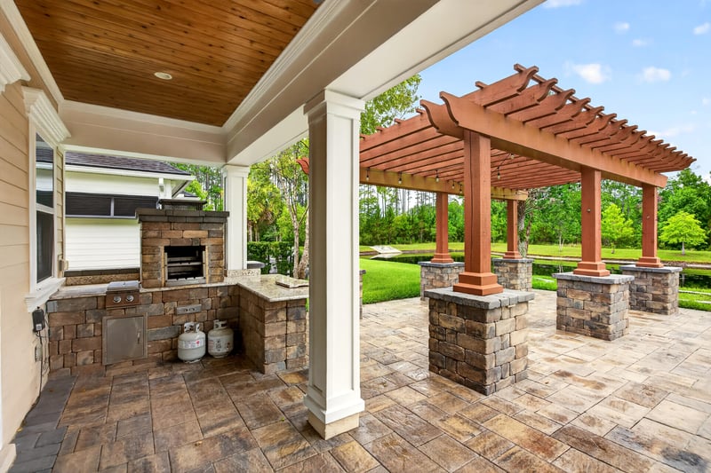 Outdoor kitchen with stone fireplace under a pergola at 186 Freshwater Dr