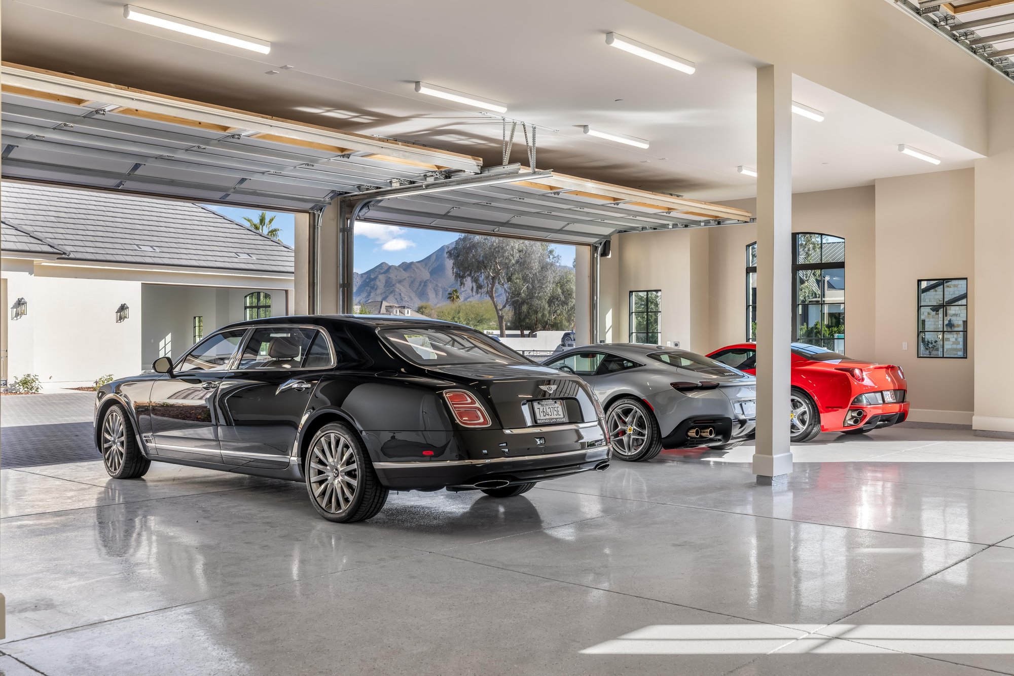 Garage with polished floors, a Bentley and two Ferraris, with the mountains through the open door