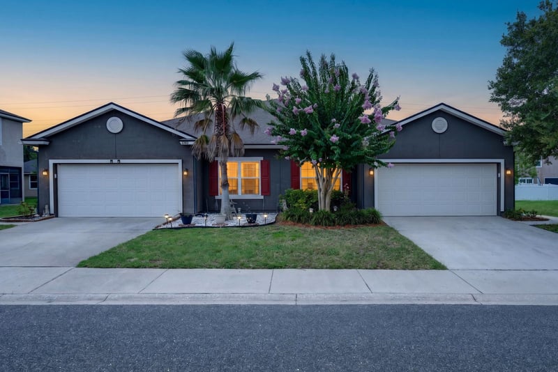Front exterior at day-to-dusk with lighted windows and palm tree at 2378 Caney Oaks Dr, Jacksonville, FL