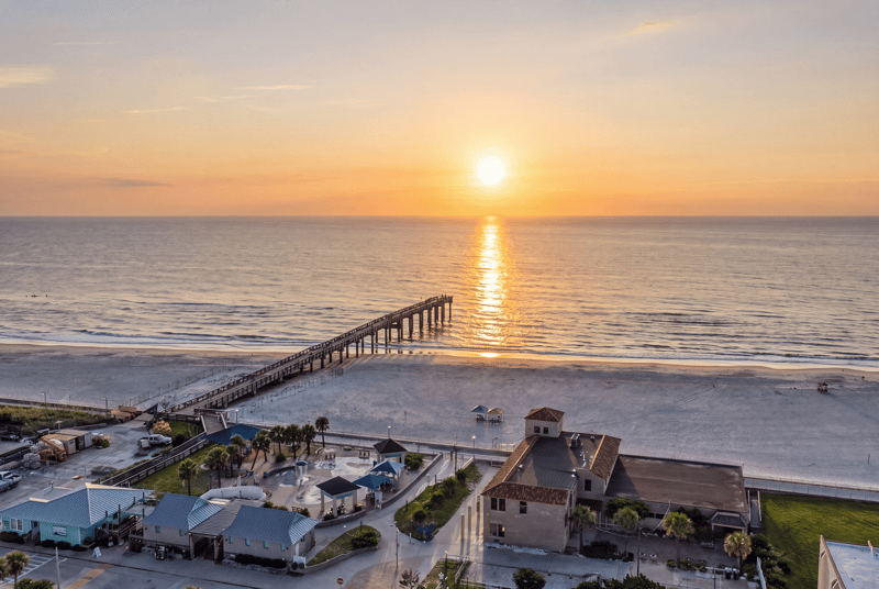 Aerial day-to-dusk view of the beach and pier in St. Augustine, FL