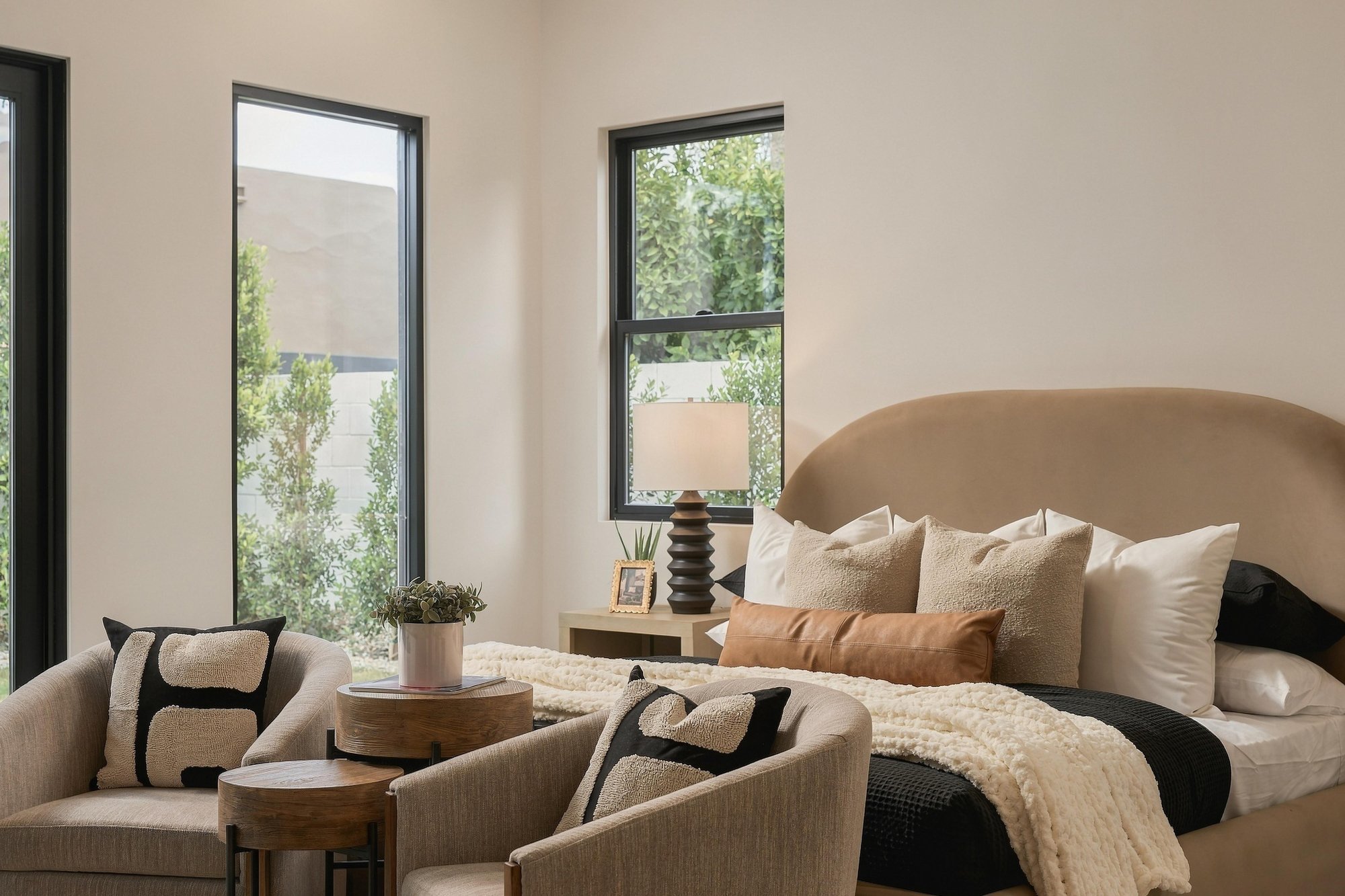 Primary bedroom with an upholstered bed and two lounge chairs