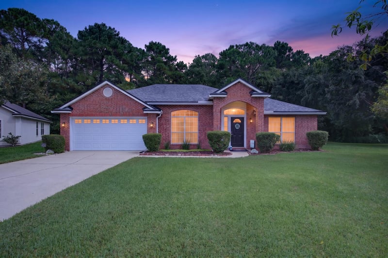 Front exterior at day-to-dusk, brick ranch home with large lawn at 13514 Las Brisas Way N, Jacksonville, FL
