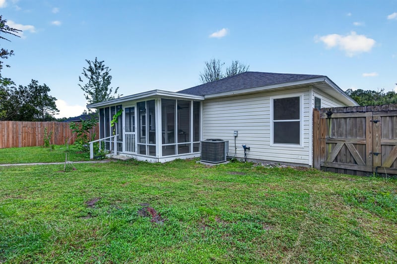 Backyard view of home and screened porch at 9691 Nelson Forks Dr, Jacksonville, FL 32222