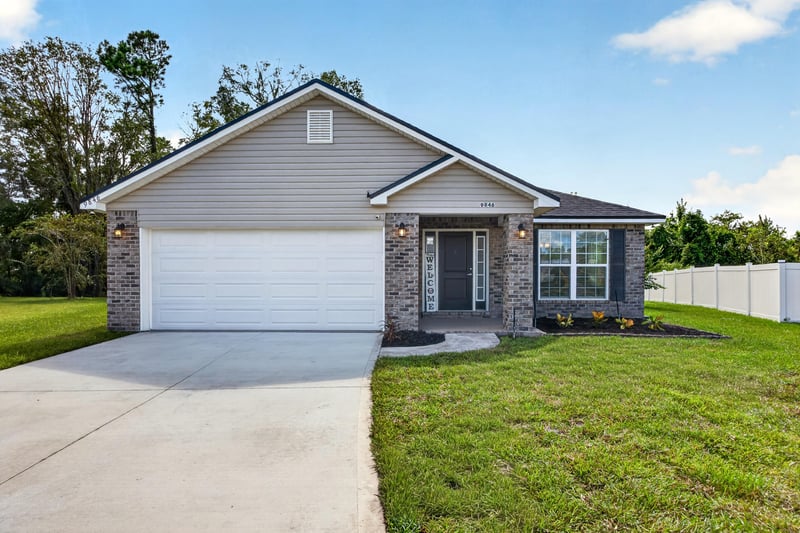 Front exterior with brick accents and paved driveway at 9846 Olivia St, Jacksonville, FL