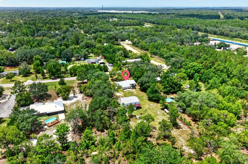 Aerial view of wooded neighborhood with distant lake in Keystone Heights, FL