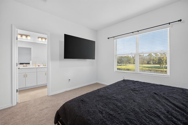 Primary bedroom with wall-mounted TV and bathroom doorway at 339 Anthony Dr, Jacksonville, FL