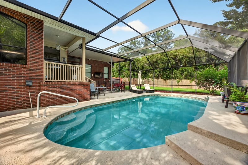 Pool with brick home and covered porch at 2125 Blue Heron Cove Dr, Orange Park, FL 32003