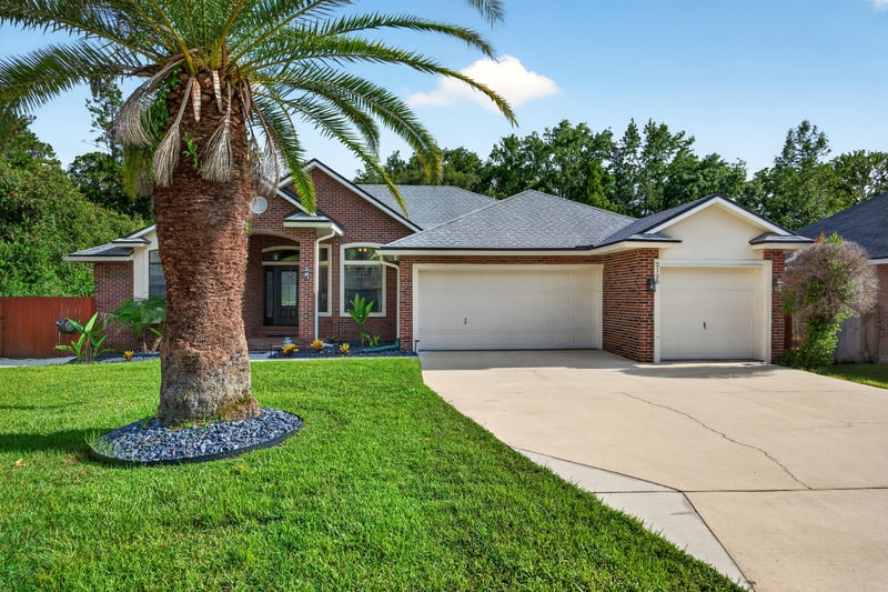 Front exterior with brick facade and palm tree at 2125 Blue Heron Cove Dr, Orange Park, FL 32003