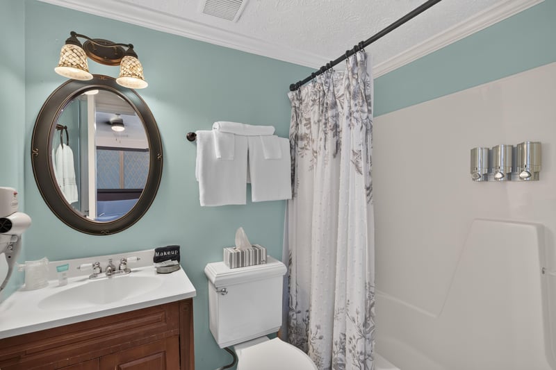 Bathroom with a round mirror and floral shower curtain at 115 Cordova St, St. Augustine, FL