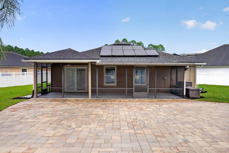 Rear exterior with solar panels and paver patio at 706 Grampian Highlands Dr, St. Johns, FL 32259