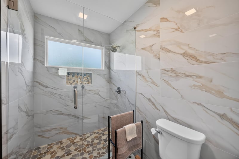 Bathroom with glass shower and marble tile at 6931 Cane Grass Ln E, Jacksonville, FL 32244