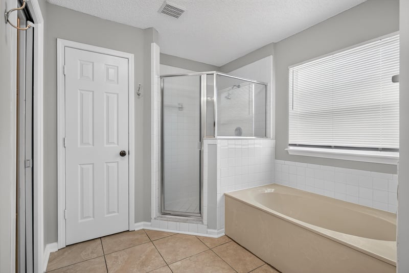 Bathroom with shower, tub, and window at 12949 Chets Creek Dr S, Jacksonville, FL 32224