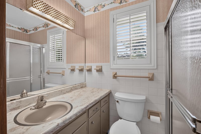 Bathroom with single vanity, shower and floral wallpaper border at 1834 Memory Ln, Jacksonville, FL