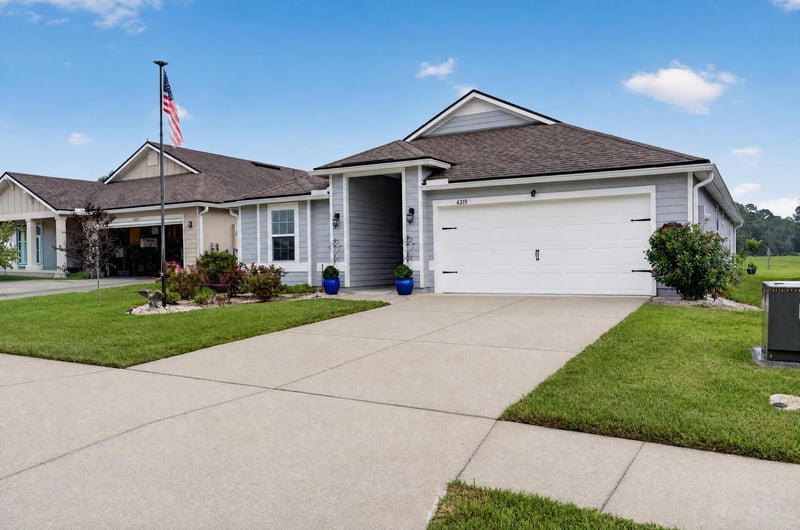Front exterior with flag pole and driveway at 4319 Green River Pl, Middleburg, FL 32068
