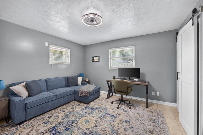 Home office with desk and sofa behind barn door at 6059 Karen St, Jacksonville, FL 32244