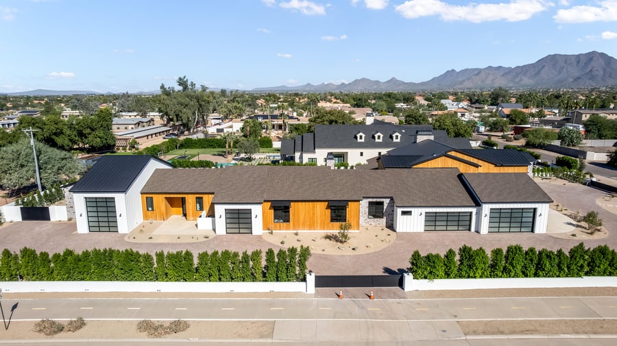 Aerial of a modern home behind a hedge wall with the mountains in the distance