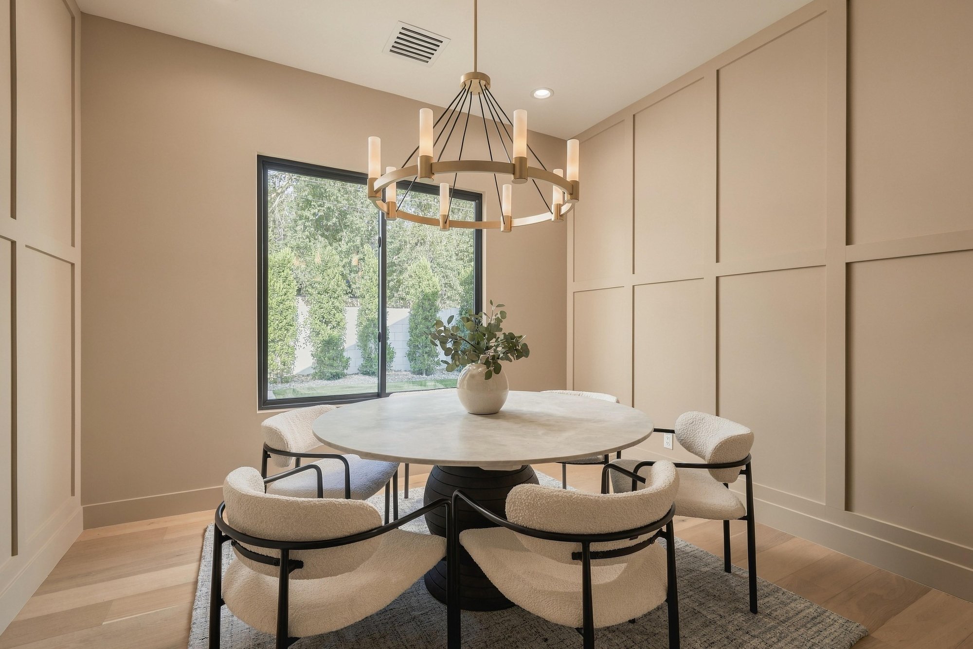 Dining room with a round stone table under a brass chandelier