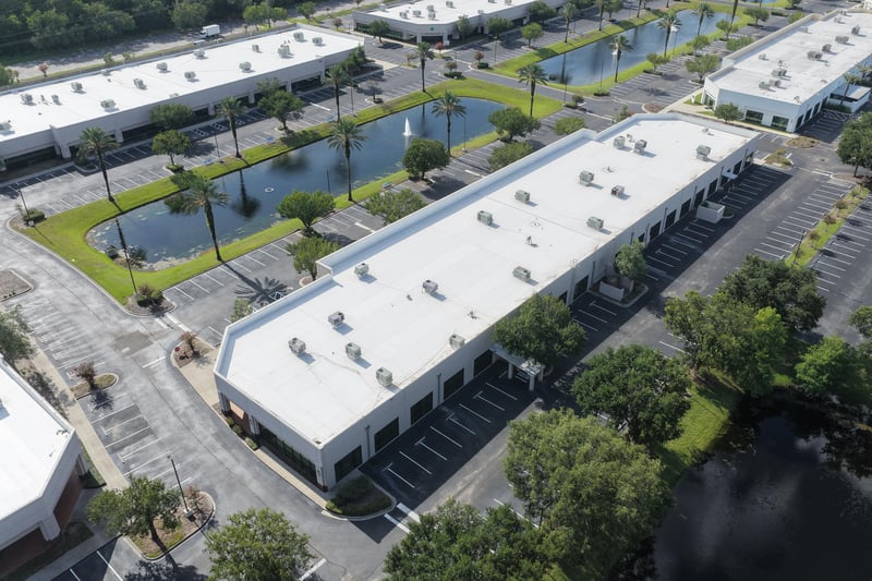 Aerial view of a building roof with parking lot and pond at 10550 Deerwood Park Blvd, Jacksonville, FL 32256