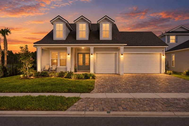 Front exterior at day-to-dusk with dormer windows and paver driveway at 27 Holly Rdg Wy, St. Augustine, FL