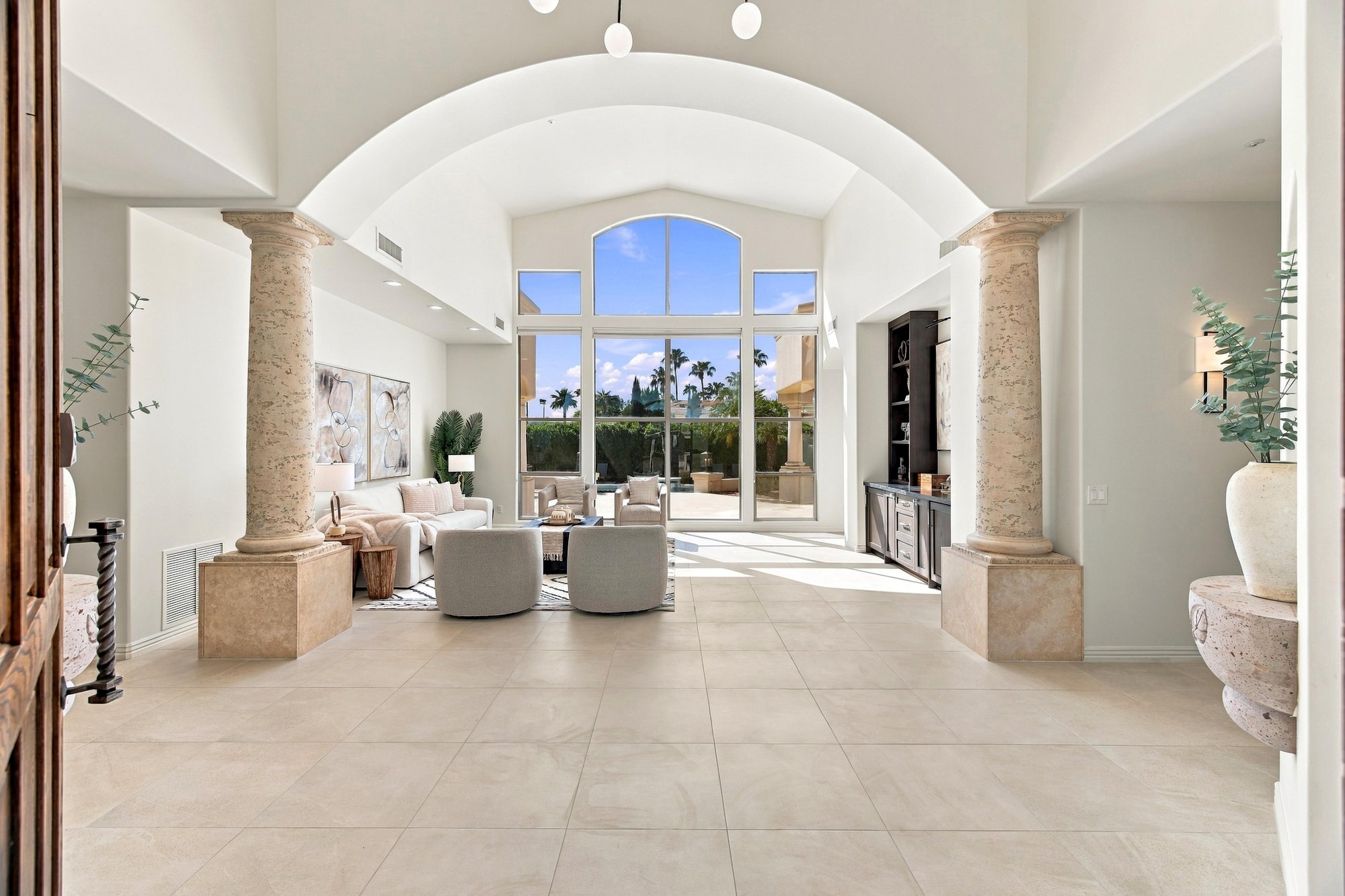 Great room under an arched ceiling with stone columns and tall windows