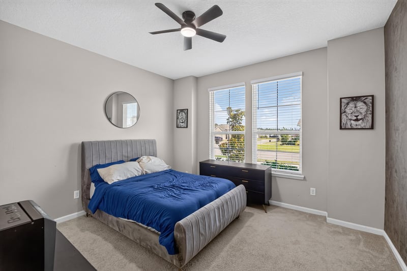 Secondary bedroom with blue bedding and round mirror at 9942 Lovage Ln, Jacksonville, FL 32219