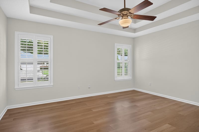 Bedroom with wood floors and plantation shutters at 2131 E Stone Creek Dr, Fleming Island, FL