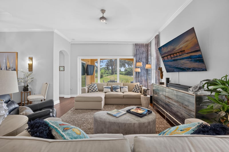 Living room with leather sofa and large windows at 140 Ave De La Mer, Palm Coast, FL 32137