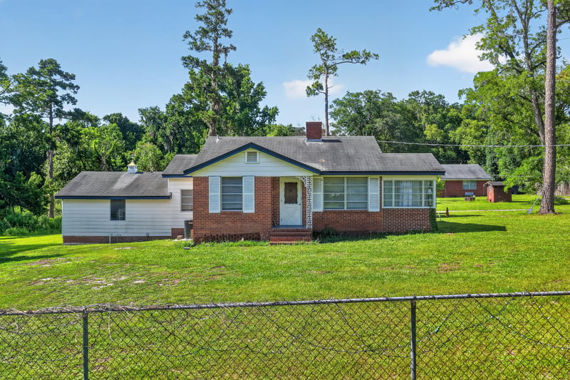 Front exterior of brick ranch home with chain-link fence and wide lawn at 5745 110th St, Jacksonville, FL 32244
