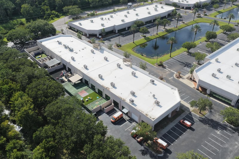 Aerial view of a building roof with delivery trucks in the lot at 10550 Deerwood Park Blvd, Jacksonville, FL 32256
