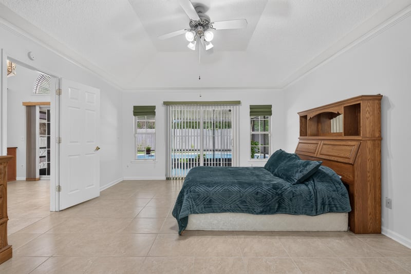 Primary bedroom with bed and pool-view windows at 12810 Swamp Owl Ln