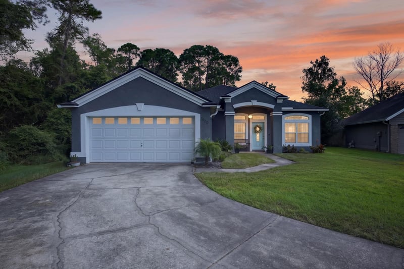 Front exterior at day-to-dusk with lit windows at 1820 Burgess Hill Dr E, Jacksonville, FL